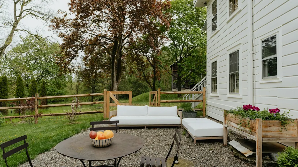 Backyard patio with table, lounge seating and a white house