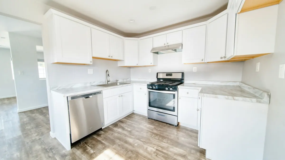 Remodeled kitchen with white cabinets and stainless appliances